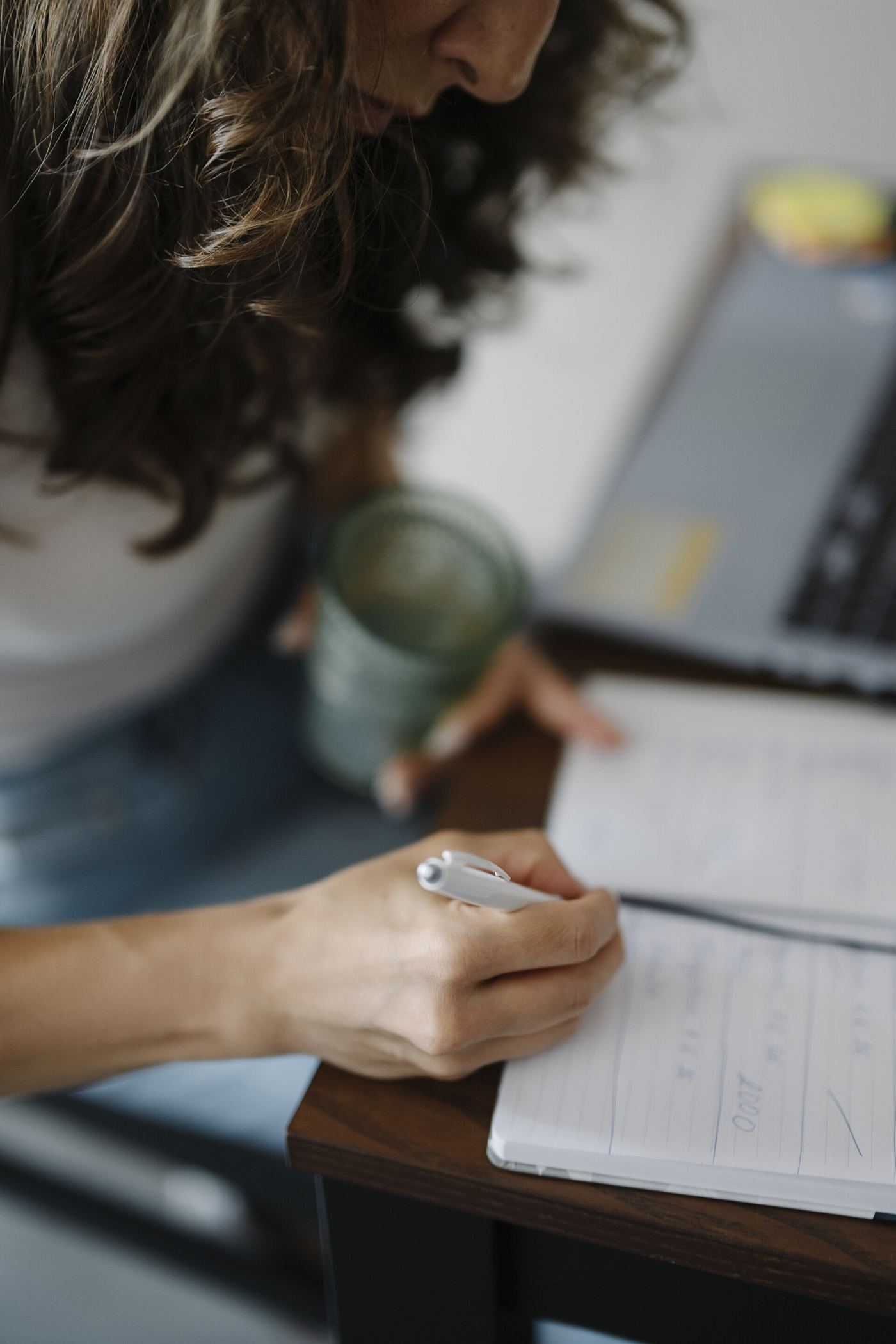 A person writing in a notebook at a tidy desk
