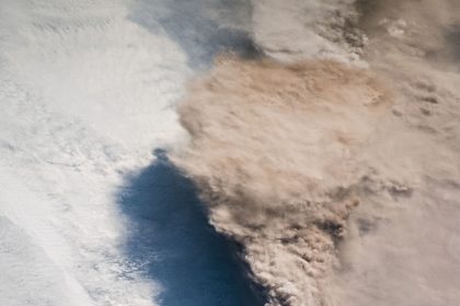 volcanic ash cloud rising above an island