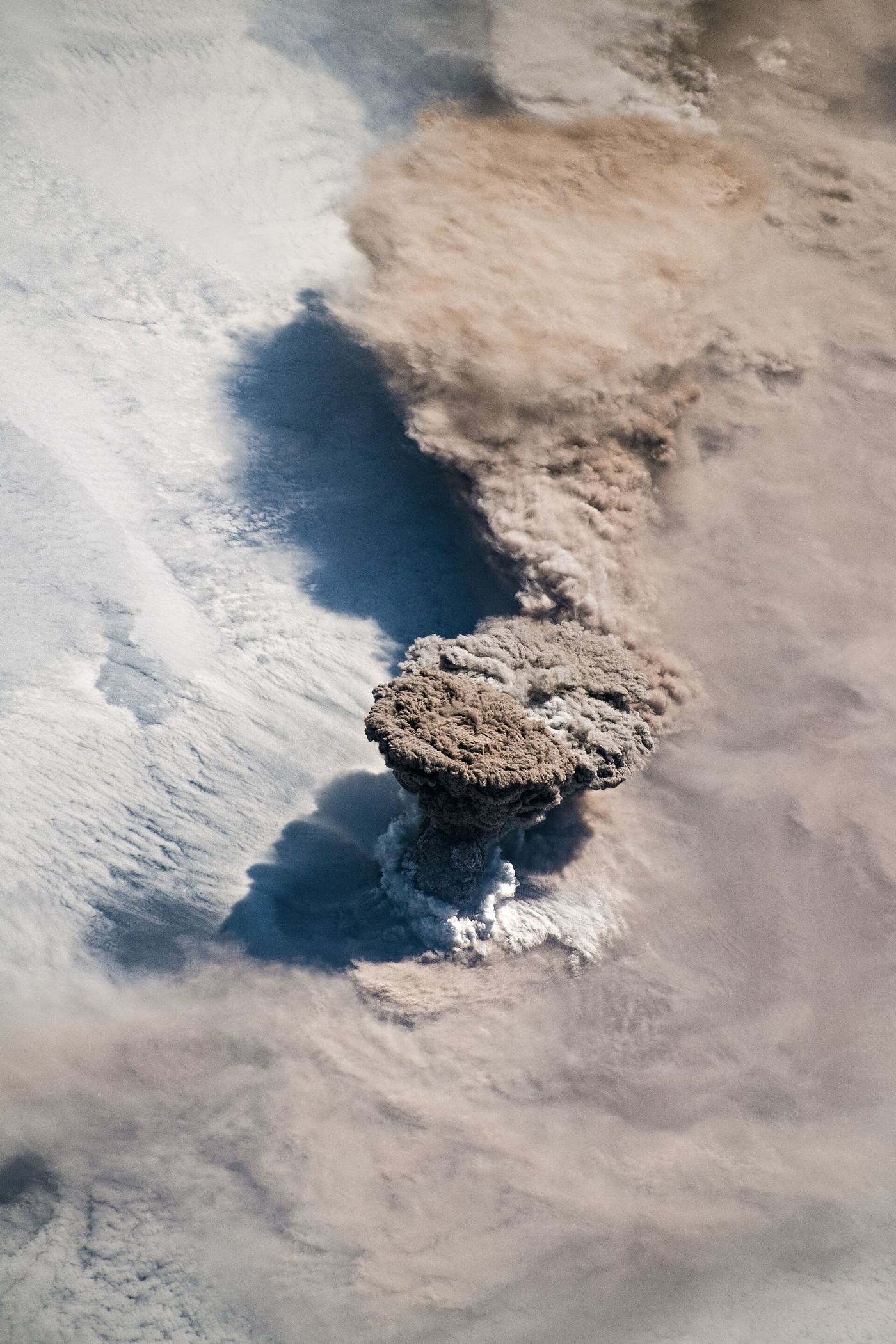 volcanic ash cloud rising above an island