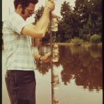 A scientist taking water samples beside a research vessel