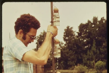 A scientist taking water samples beside a research vessel