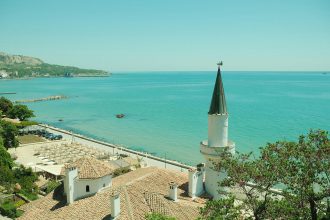 A dry Mediterranean coastline with parched land above a blue sea.