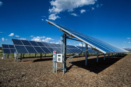 Rows of solar panels stretching across desert land under a clear sky.