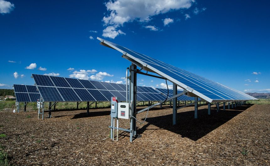 Rows of solar panels stretching across desert land under a clear sky.