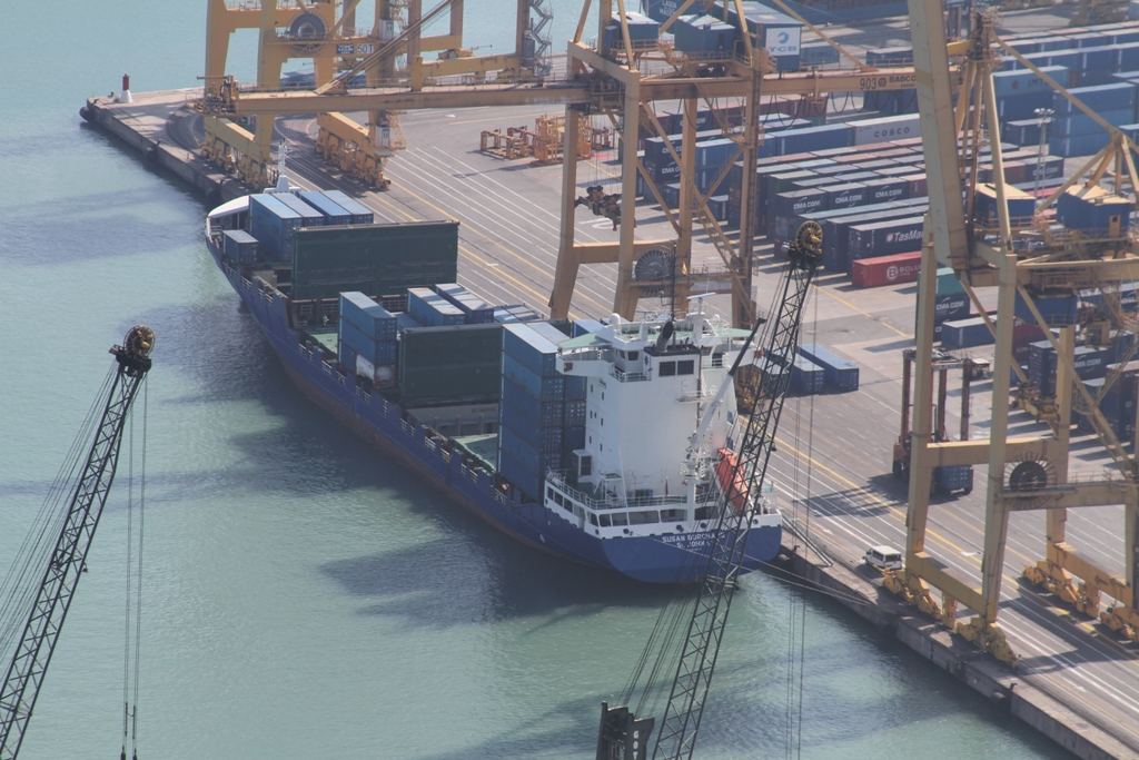 A container ship being loaded by cranes at a busy port